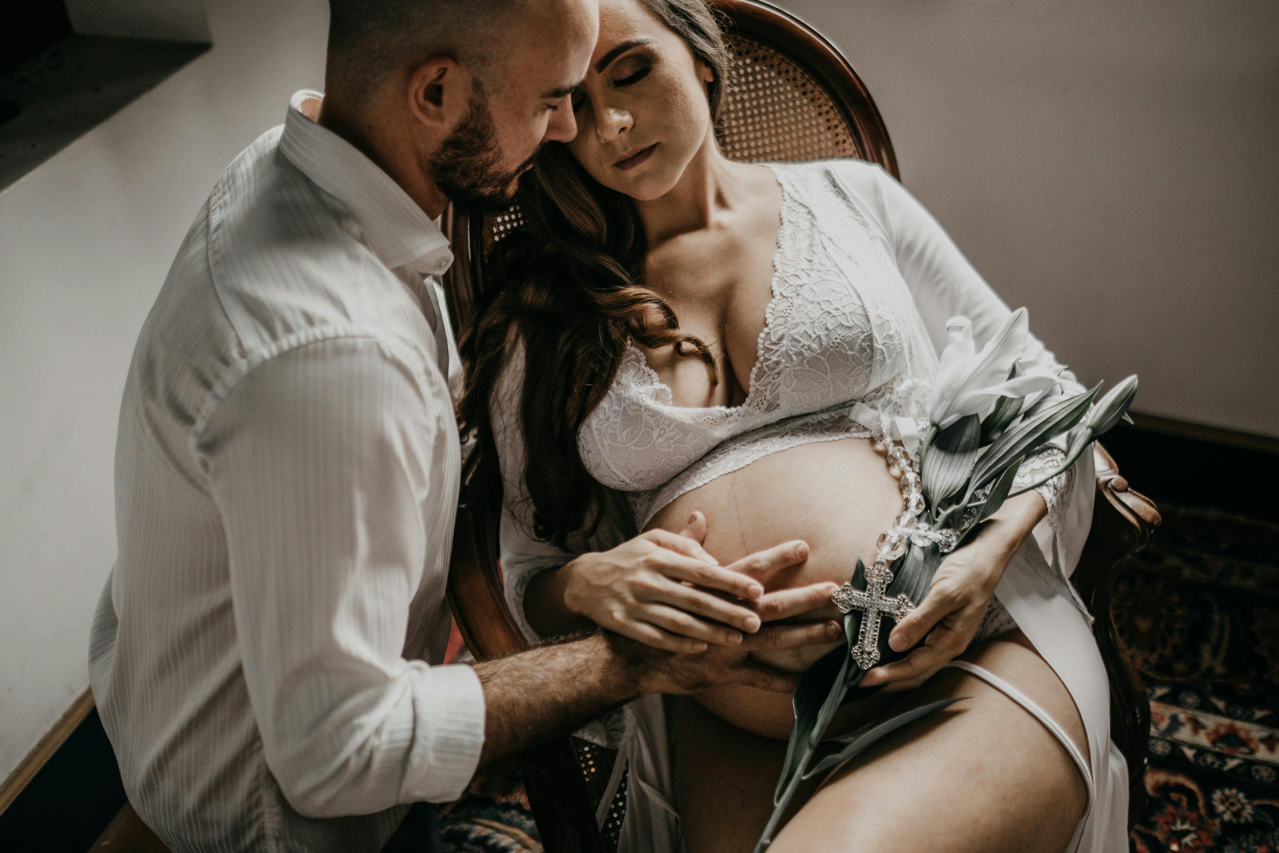 An expecting couple shares a tender moment during a maternity photoshoot at home.